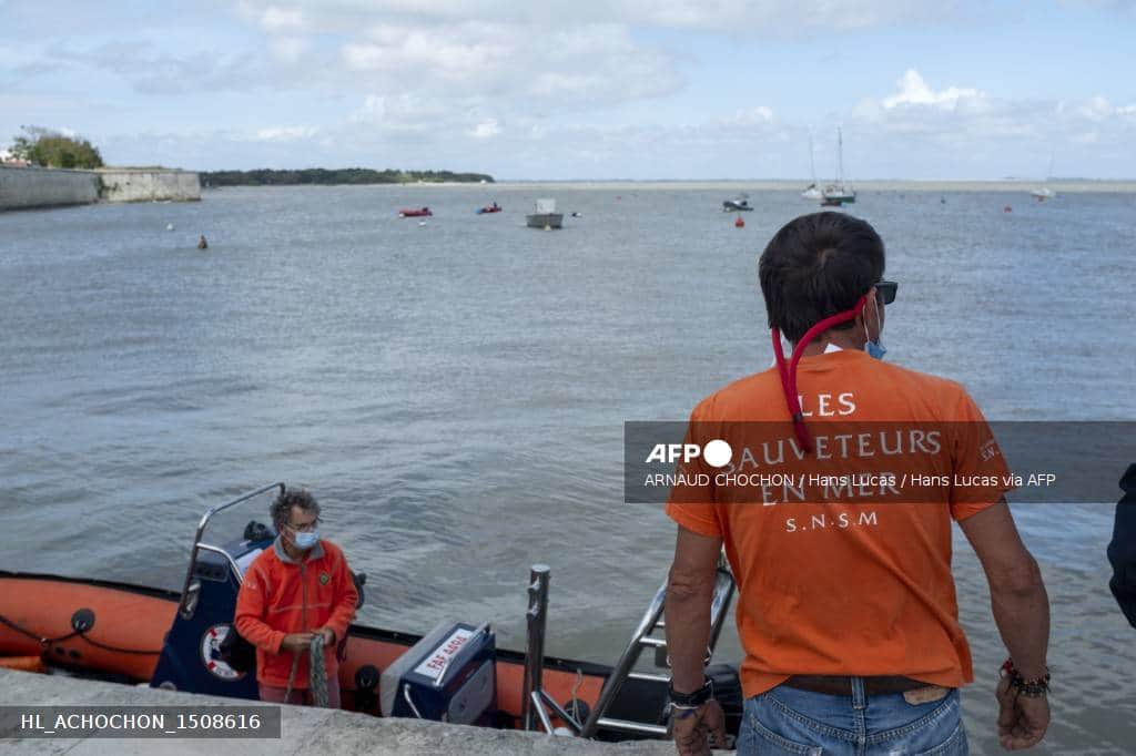 Deux sauveteurs de la SNSM près de leur bateau de secours, sur le littoral.