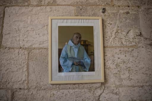 Portrait encadré du père Jacques Hamel accroché au mur de pierre de son église